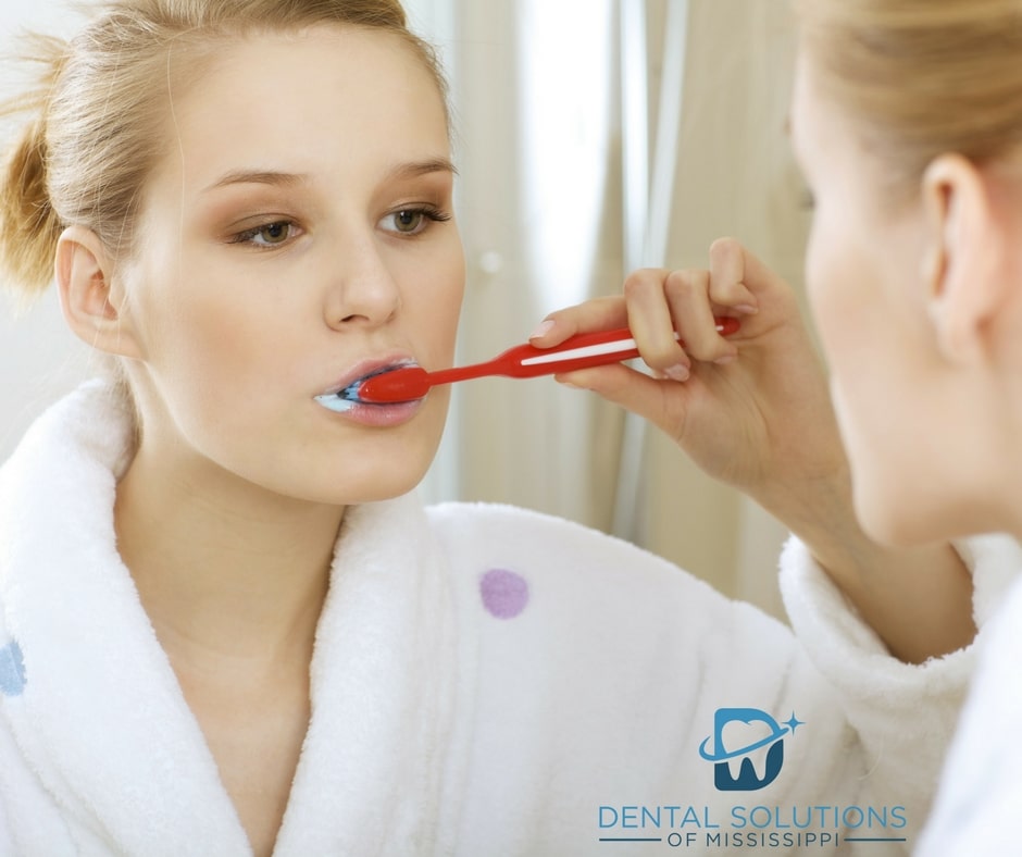 Woman brushing her teeth Dental Solutions of Mississippi dentist in Canton MS Dr. Ruth Roach Morgan Dr. Jessica Morgan