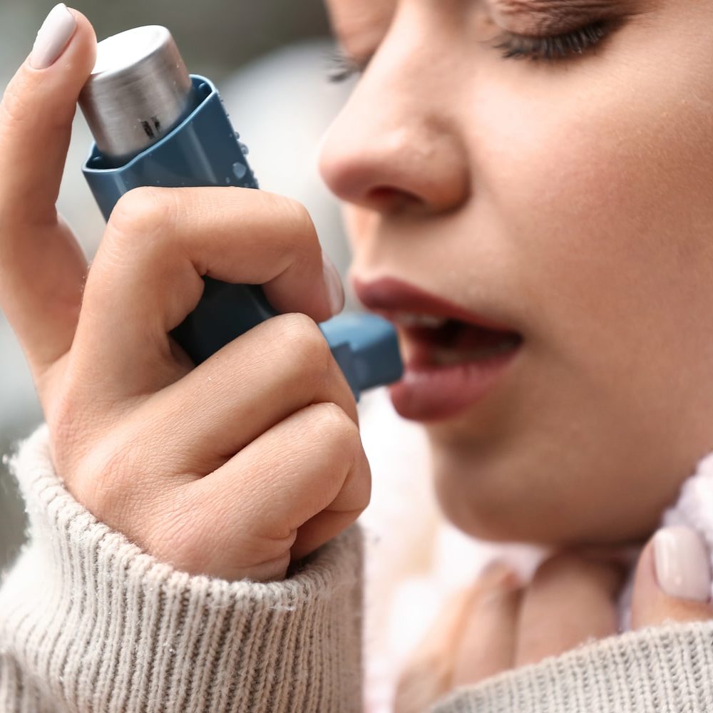 Woman using asthma inhaler