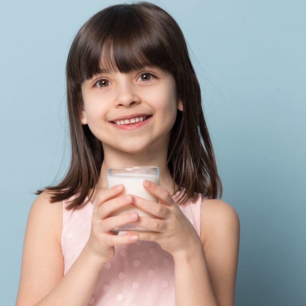 Smiling child holding glass of milk